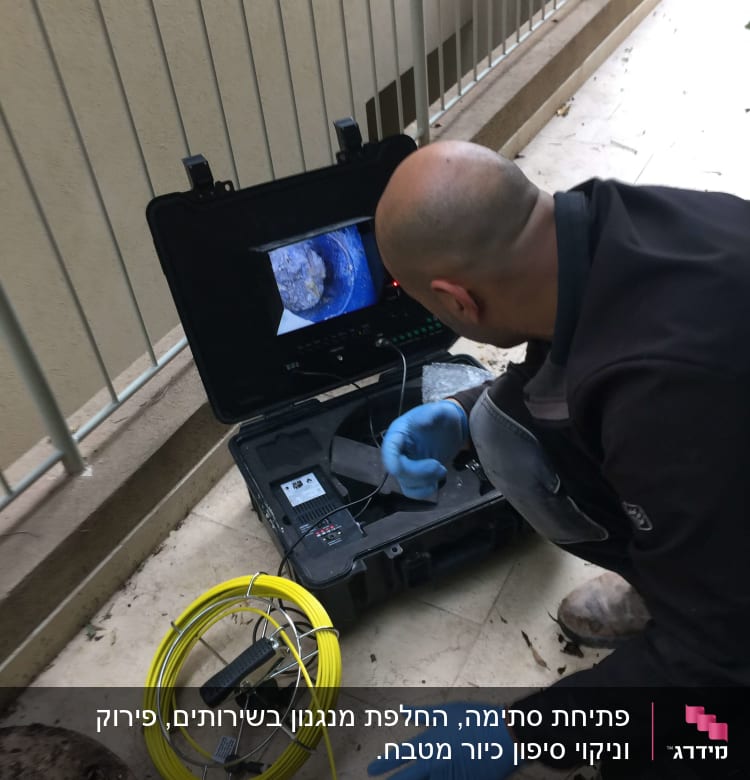 אדם עם כפפות כחולות משתמש במצלמת ביוב